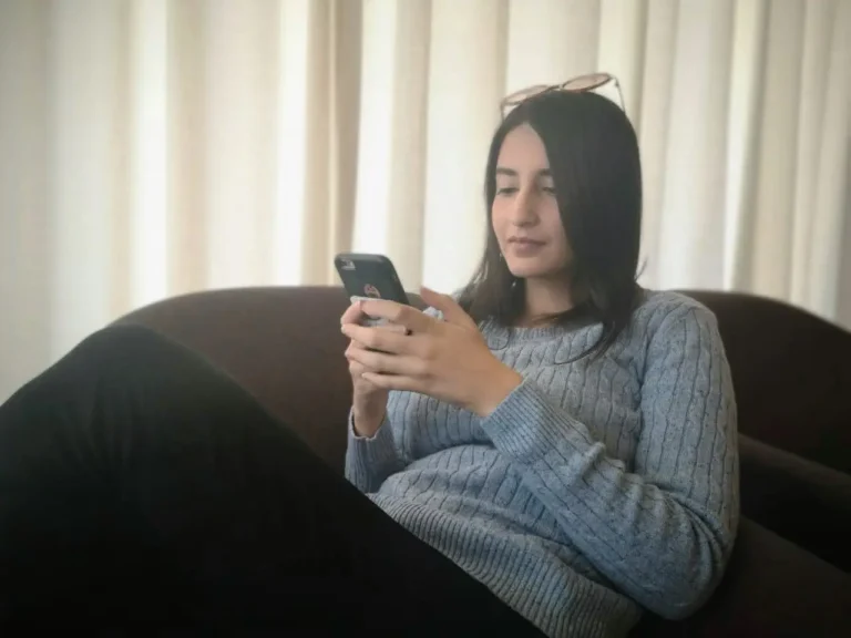 An image of the blogger sitting on a sofa chair using her phone thanks to travel sims.