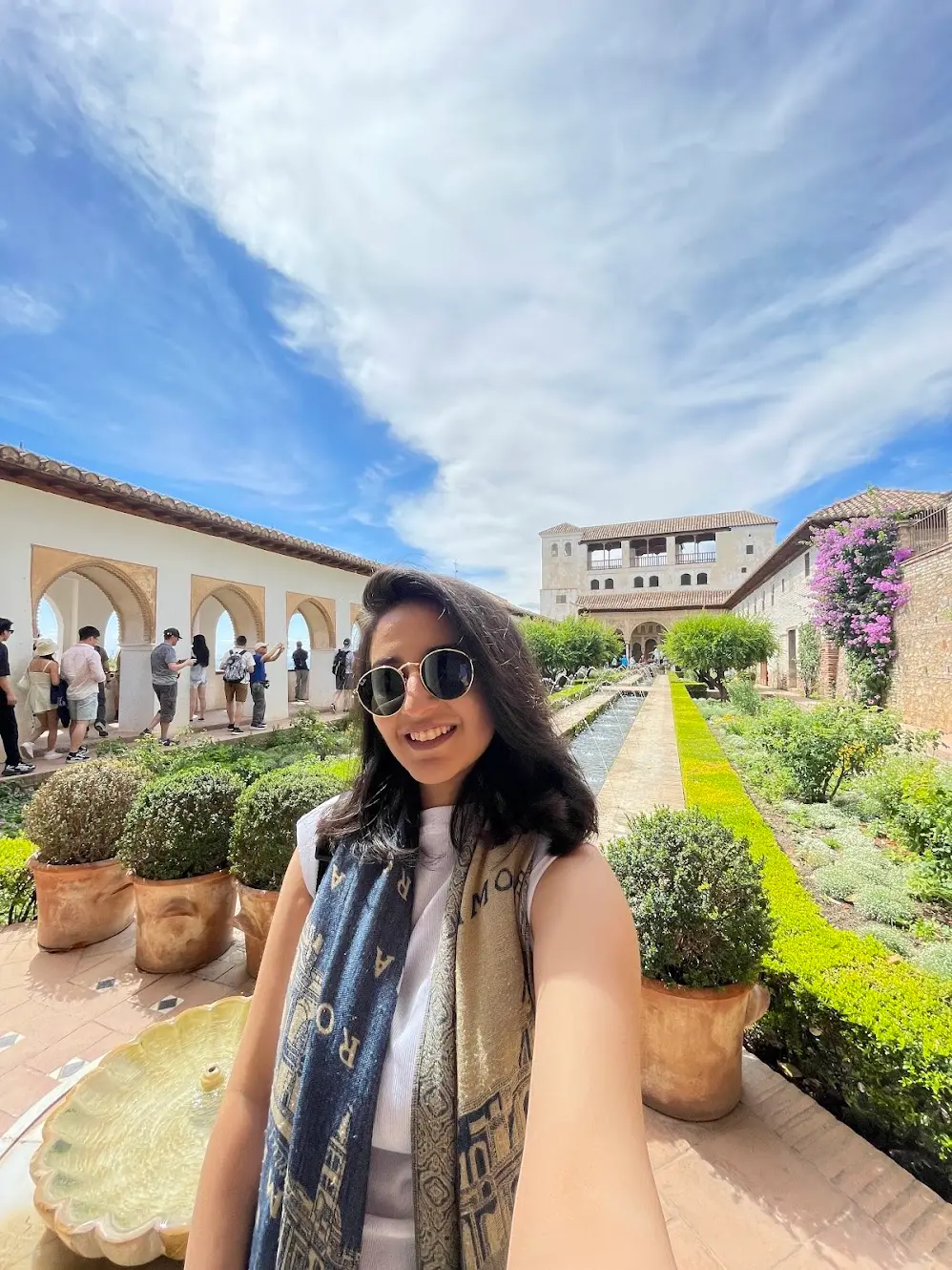 Blogger is taking a selfie and smiling while wearing sunglasses at Alhambra, Spain