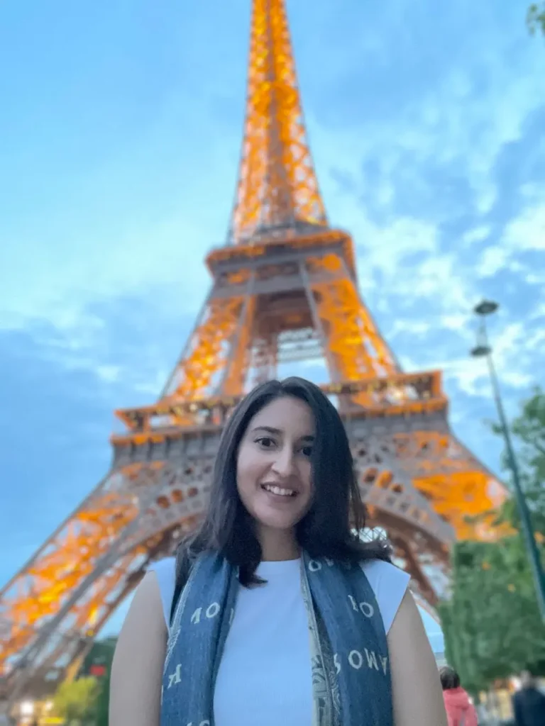 Blogger smiles in front of the sparkling Eiffel Tower in Paris, France