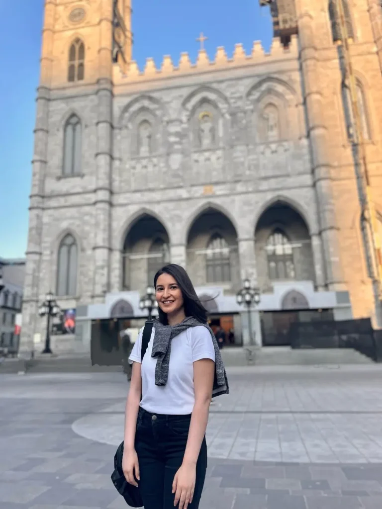 Blogger is smiling and standing in front of the Notre-Dame Basilica of Montreal, Canada.
