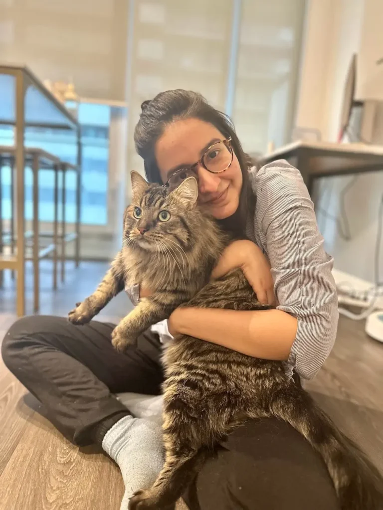 The blogger is sitting on the floor and holding a cat doing biscuits in the air.