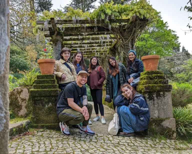 Group photo in Sintra, Portugal. 6 women and 1 man are smiling into the camera in the greenery.