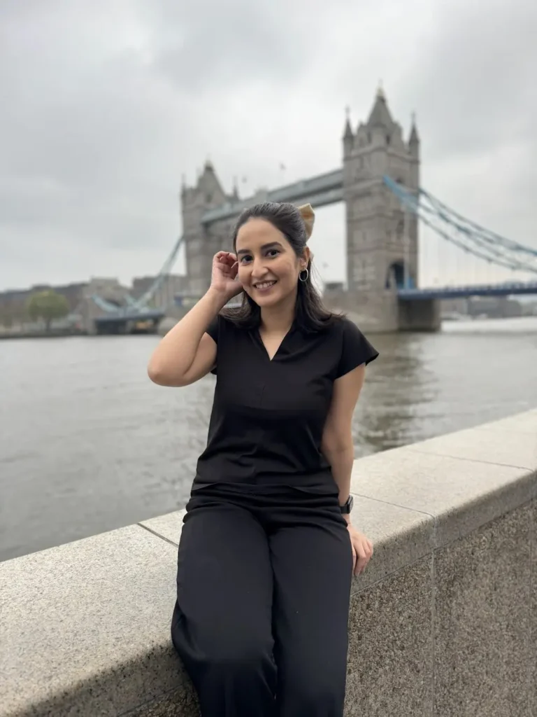 Image of the blogger smiling with the Tower Bridge in the background, during her trip to London UK where she was  house sitting.