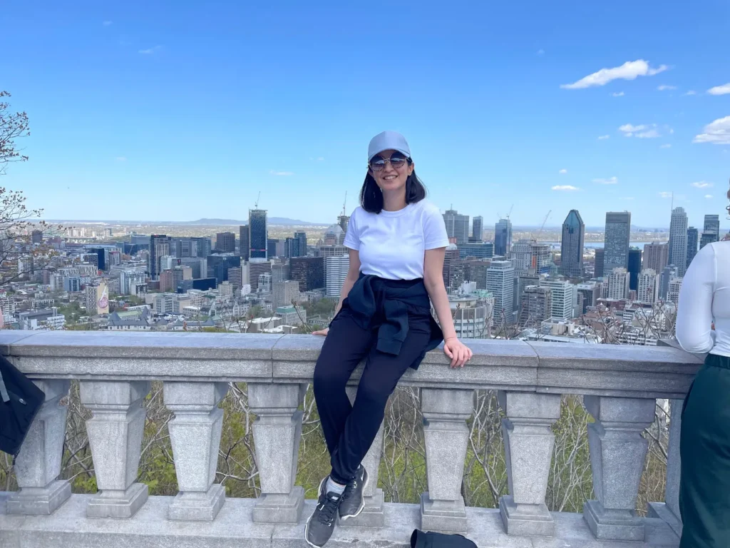blogger smiling and sitting on a ledge against the backdrop of montreal, quebec, canada